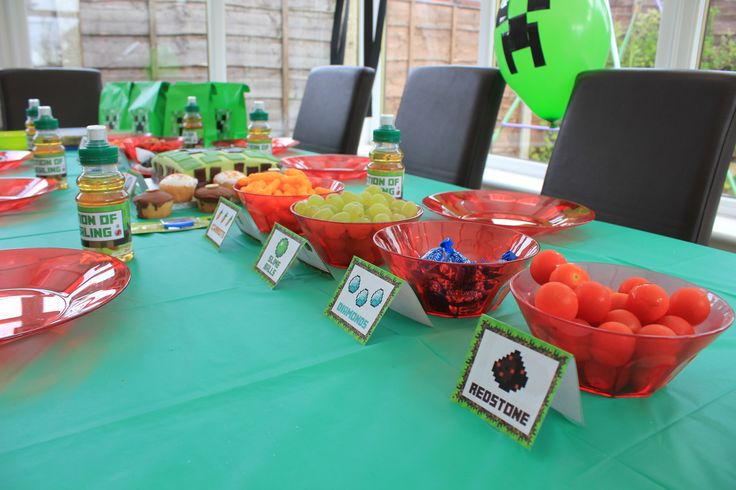 the table is set up for a party with fruit in bowls and place cards on it