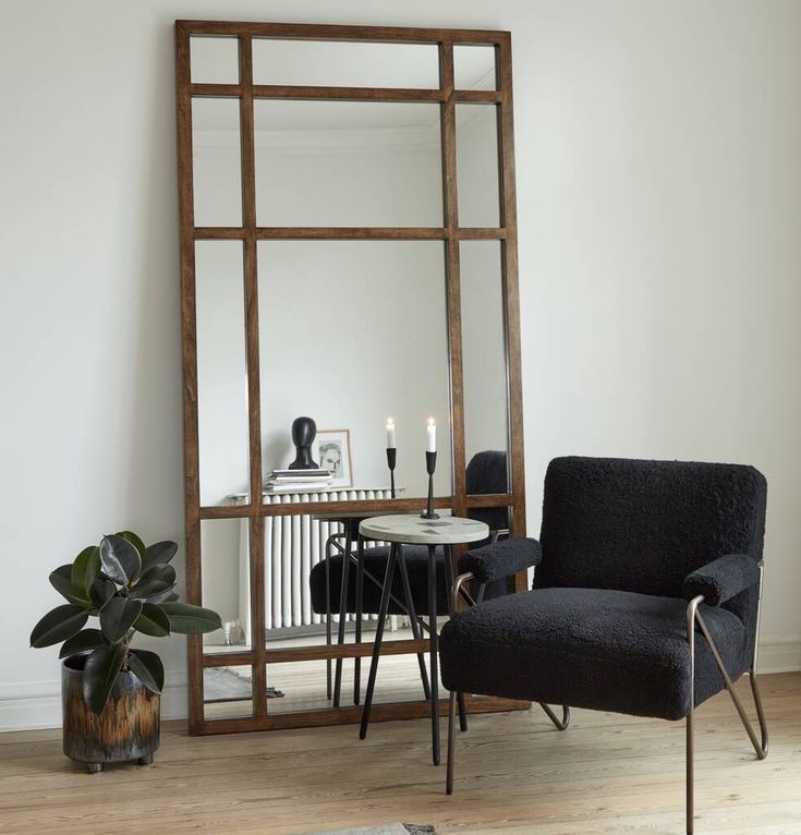 a living room with a chair, mirror and table