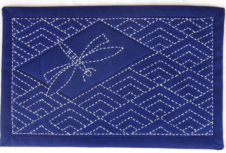 a blue table cloth with white stitching on it and a bow in the center