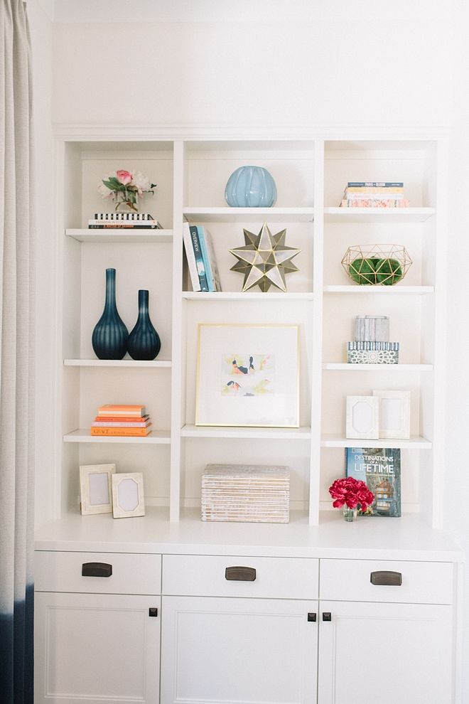 a white bookcase filled with books and vases on top of it's shelves