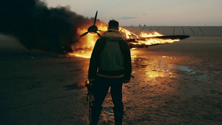 a man standing in front of an airplane on fire