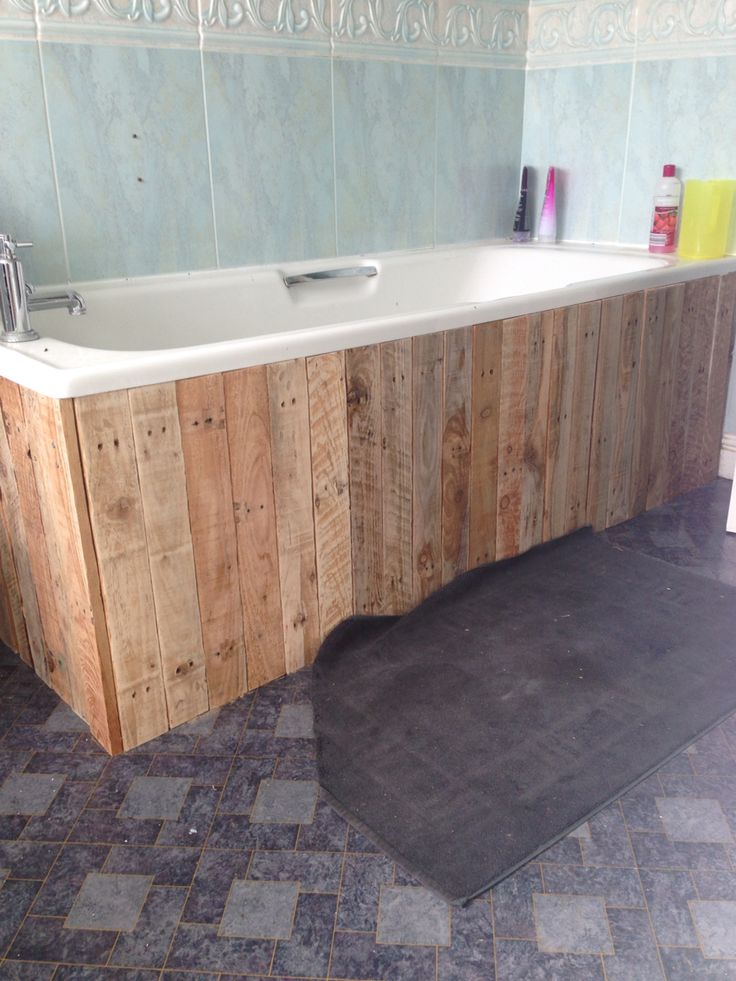 a bathtub made out of pallet wood in a bathroom with tile flooring