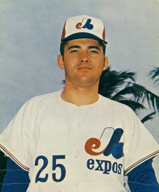 a baseball player in a white and blue uniform is posing for a photo with palm trees behind him