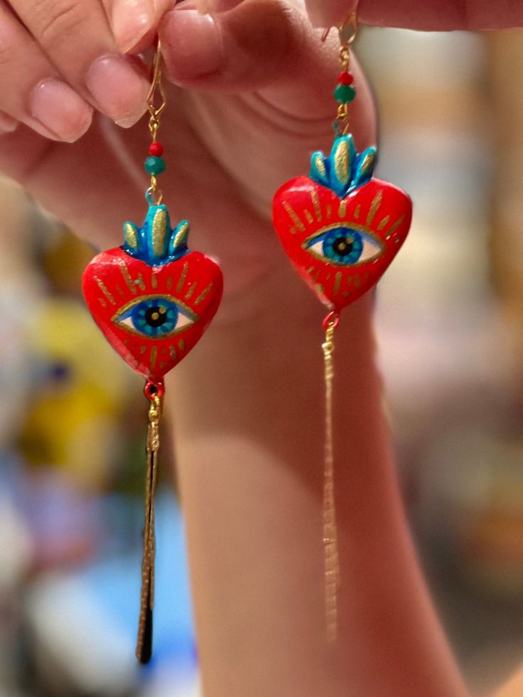 Heart shaped pendant earrings handmade by Edith Orozco, from Leon, Guanajuato, Mexico! Edith paints each heart amulet by hand, then carefully sets them in gold plated fixtures. Every piece is unique. Artisan Heart Earrings For Pierced Ears As Gift, Artisan Heart Earrings As Gift, Artistic Heart Earrings As Gift, Handmade Heart-shaped Jewelry For Festivals, Artistic Heart-shaped Earrings For Gift, Artistic Dangle Heart Earrings As Gift, Artistic Dangle Heart Earrings For Gift, Artistic Heart-shaped Dangle Earrings Gift, Artistic Heart-shaped Dangle Earrings For Gift