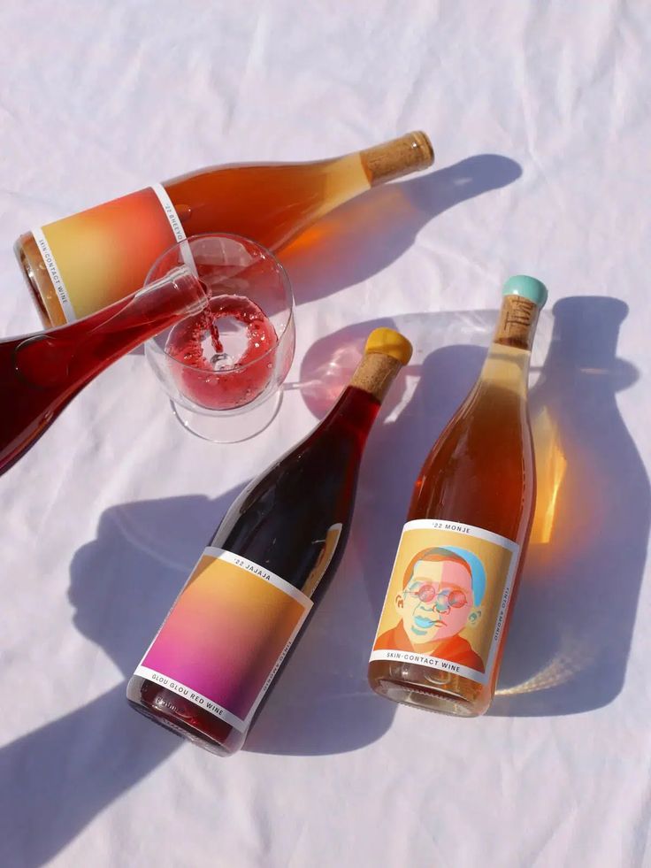 three bottles of wine sitting on top of a white table covered in food and drink