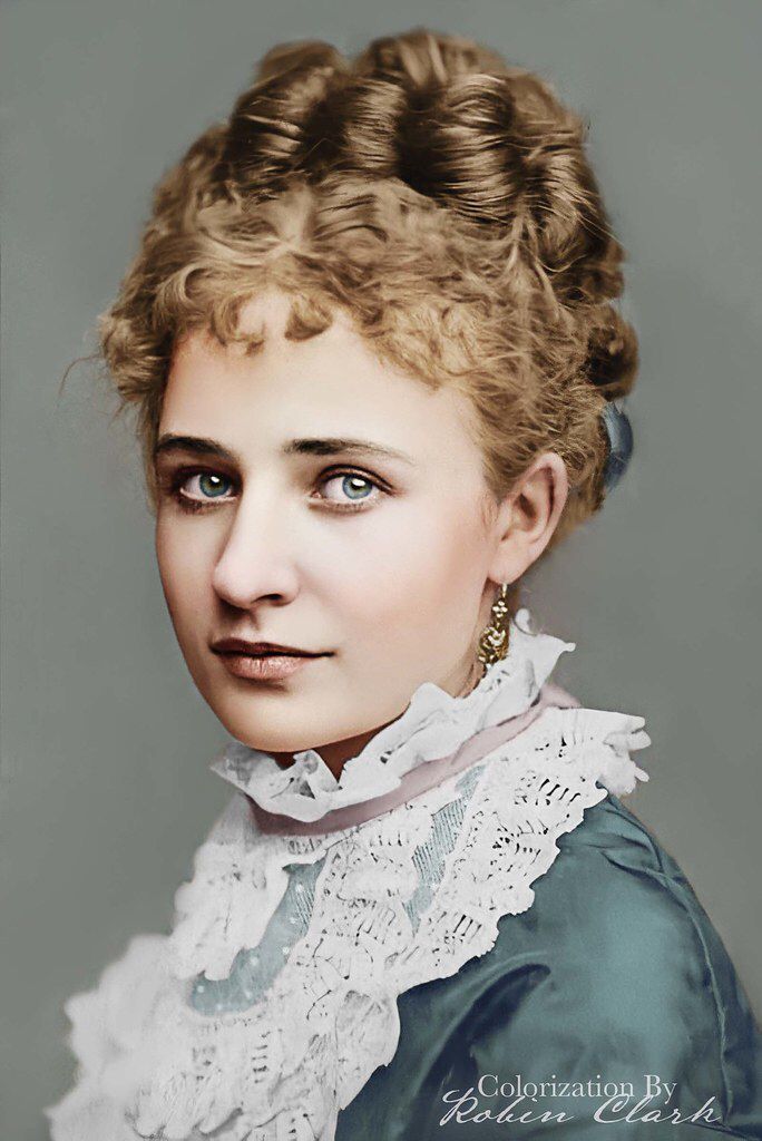 an old photo of a woman wearing a blue dress and white lace collared shirt