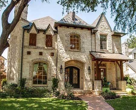 a large brick and stone house with trees in the front yard