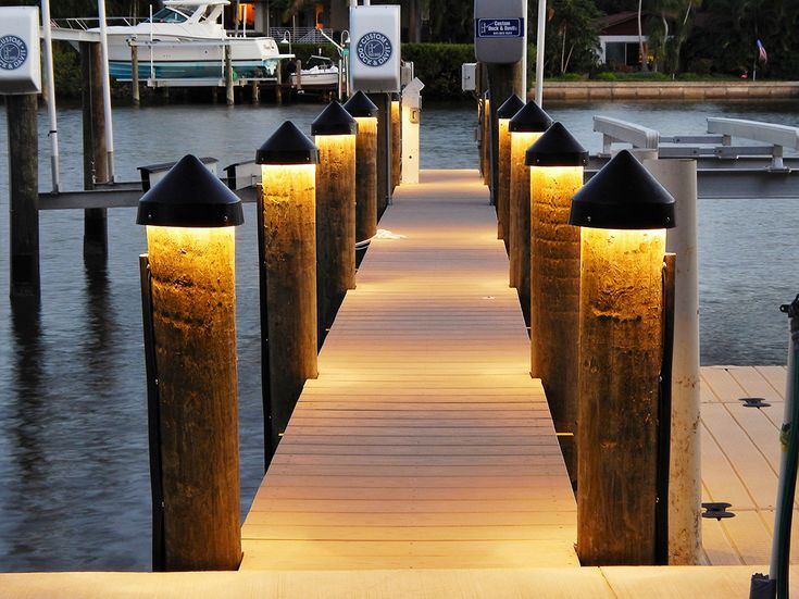 a wooden dock with lights on it next to the water