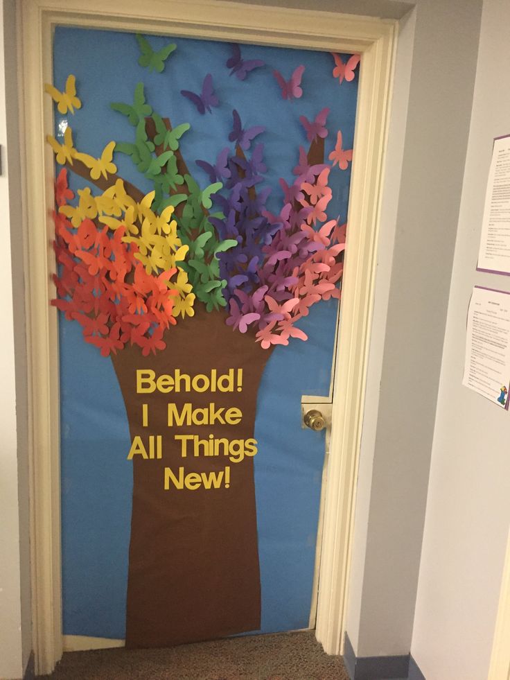 a door decorated with colorful paper flowers and the words behold i make all things new