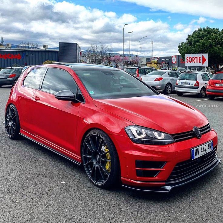 a red car parked in a parking lot next to other cars