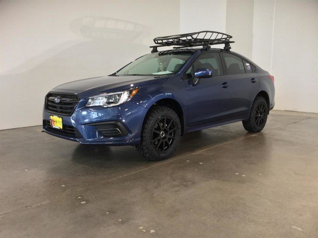 a blue subarunt parked in a garage with a ski rack on the roof