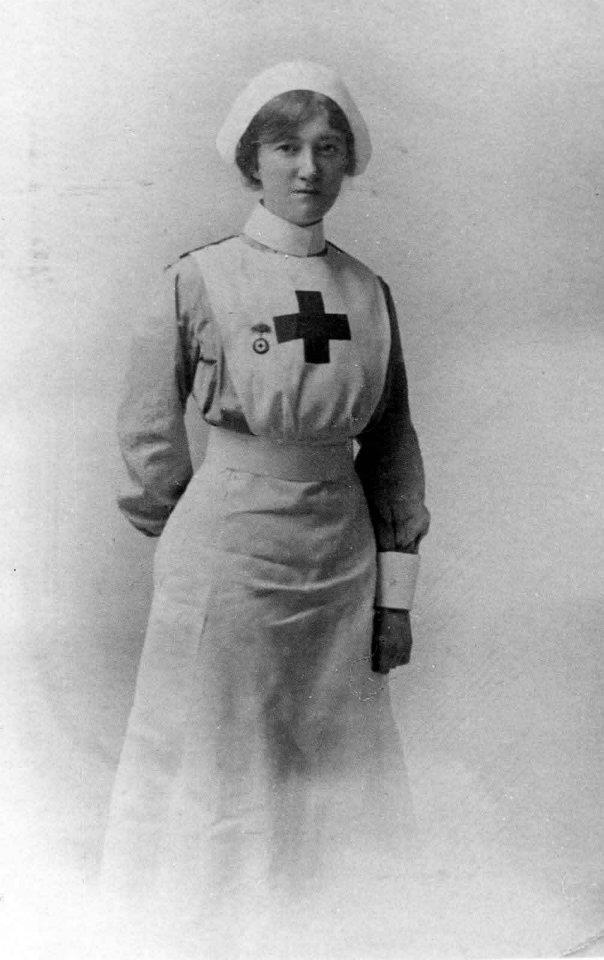 an old black and white photo of a woman wearing a nurse's uniform with a cross on it