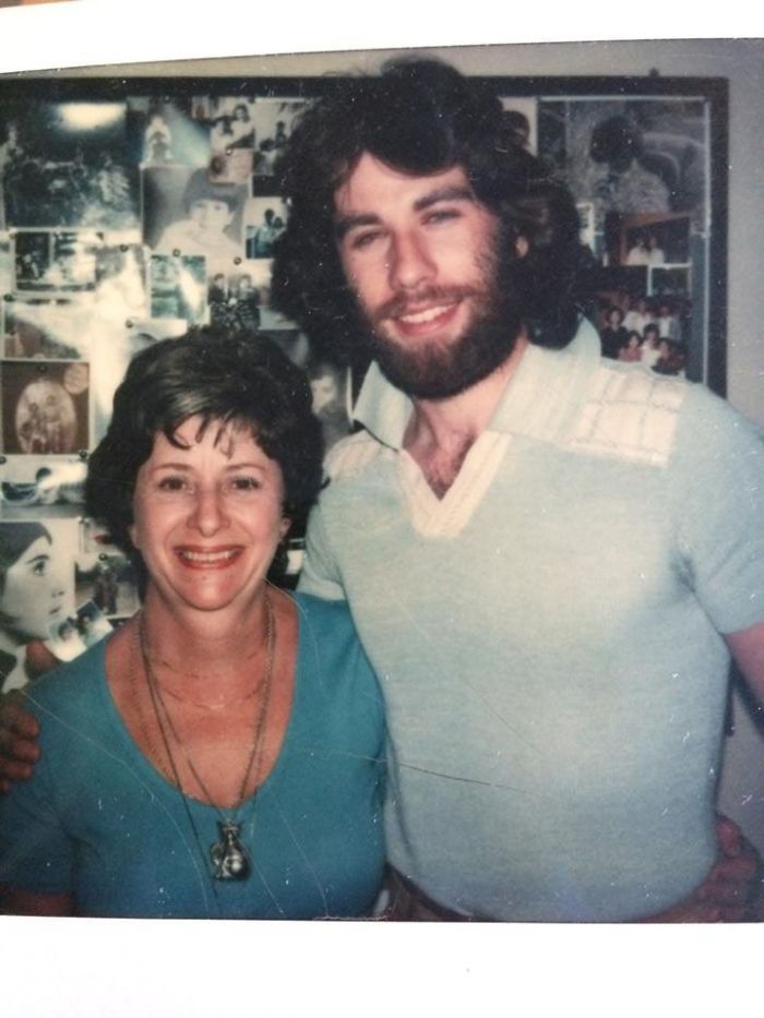 a man and woman standing next to each other in front of a wall with pictures on it