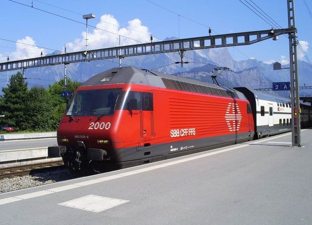 a red train traveling down tracks next to a mountain