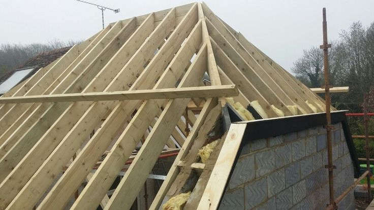 a house being built with wooden framing and roof trusses on the side of it