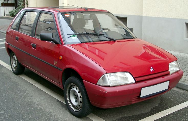 a red car is parked on the side of the road