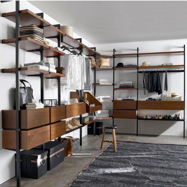 an open closet with shelves, drawers and clothes hanging on the wall next to it