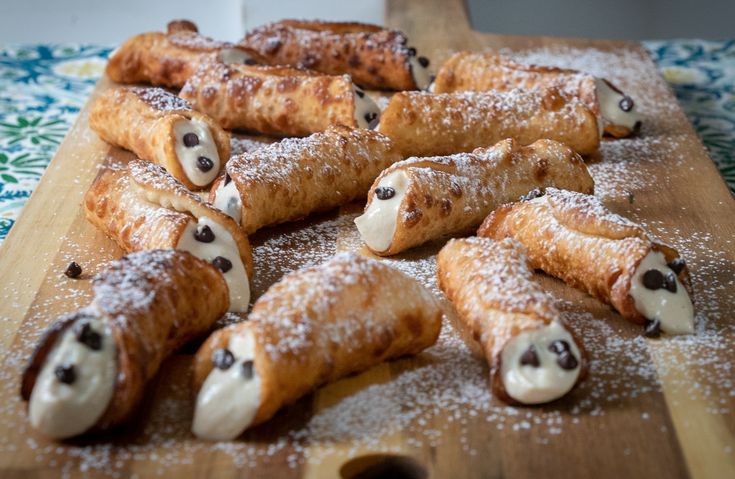 several pastries are arranged on a wooden board with powdered sugar and chocolate chips