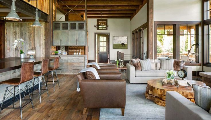 a living room filled with lots of furniture and wooden flooring next to tall windows