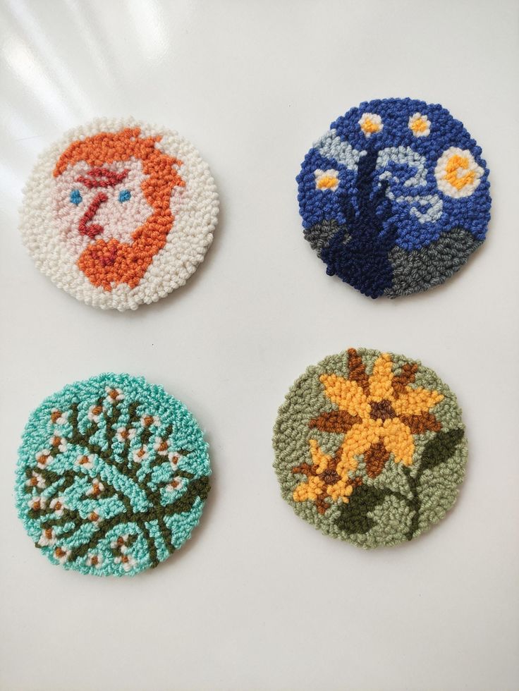 four crocheted coasters with different designs on them