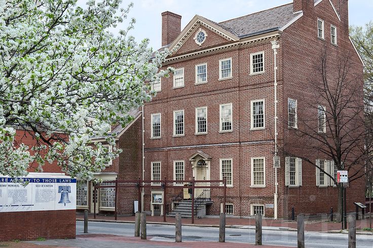 an old brick building on the corner of a street with trees in front of it