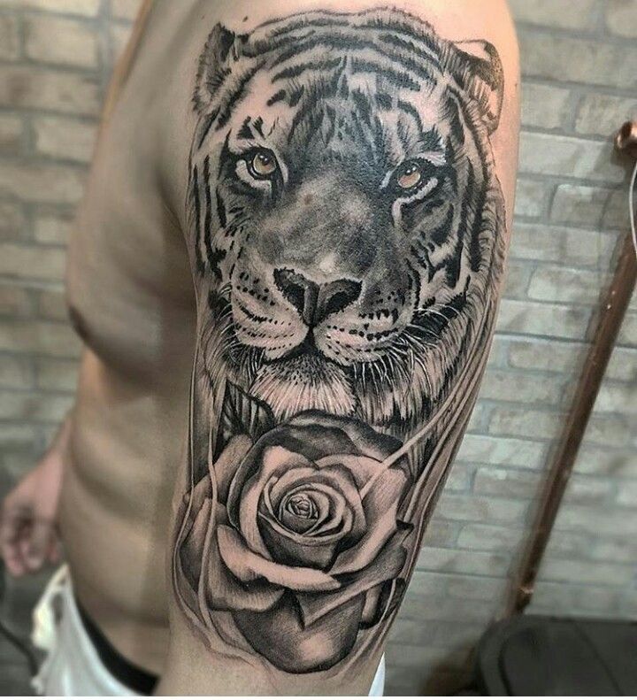 a black and white tiger with a rose tattoo on the left upper half of his arm