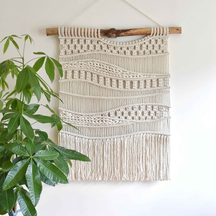 a white wall hanging next to a potted plant