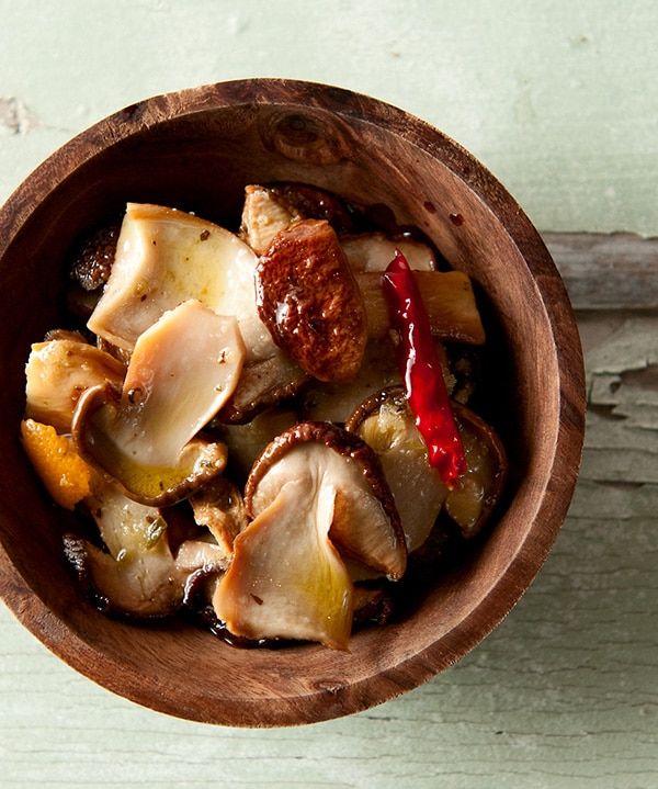 a wooden bowl filled with food sitting on top of a white table next to a green wall