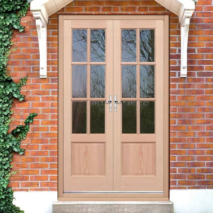 two double doors are shown in front of a red brick wall with ivy growing on it