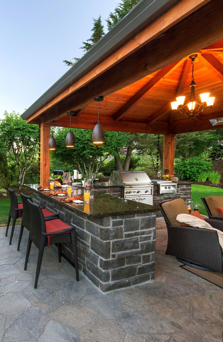 an outdoor kitchen with grill and seating area