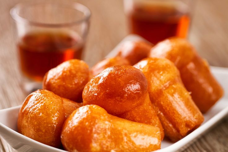 a white bowl filled with donuts next to a cup of tea