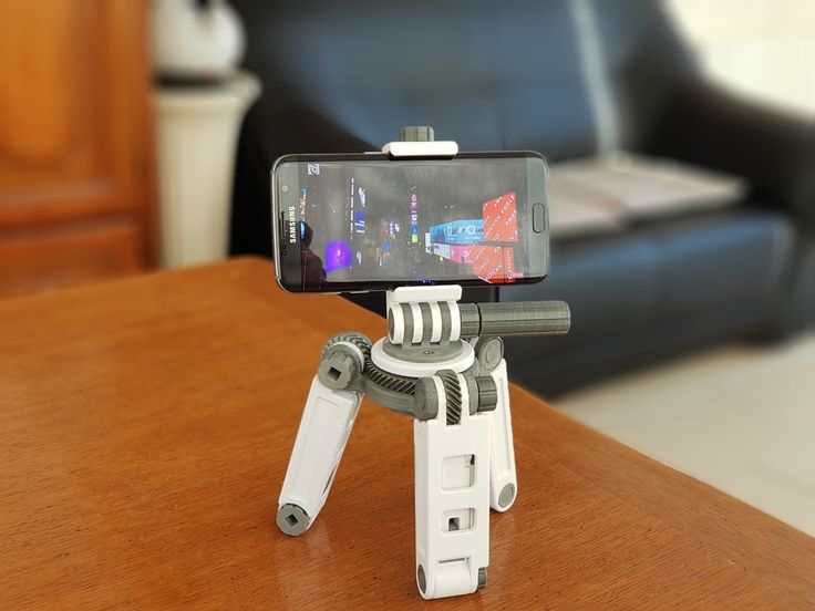 a small tripod sitting on top of a wooden table with a cell phone attached to it