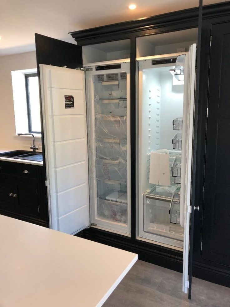 an empty refrigerator in a kitchen next to a counter and cabinets with lights on them