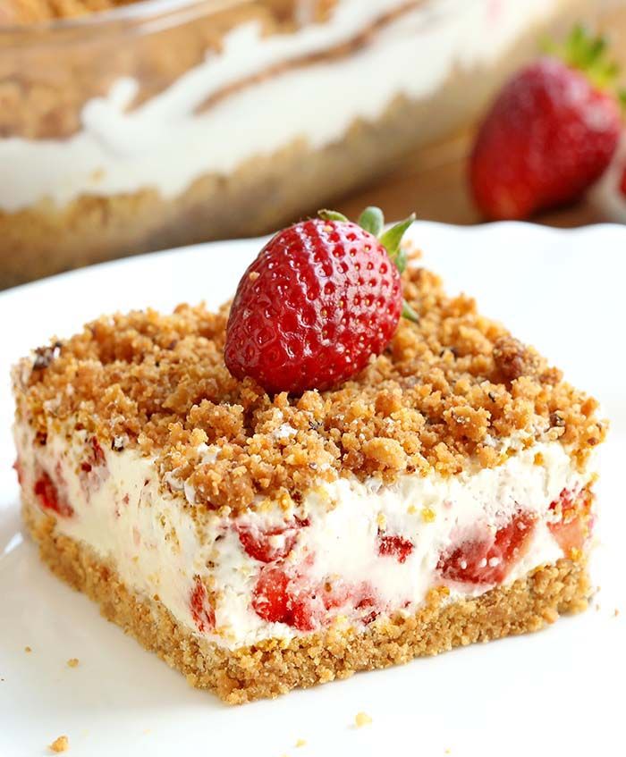 a piece of strawberry crumb cake on a white plate with strawberries in the background