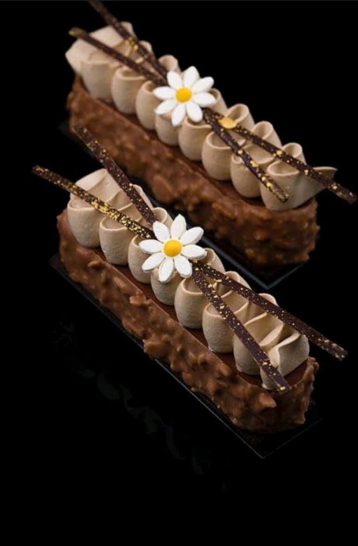 two pieces of chocolate cake with white flowers on top and gold trim around the edges