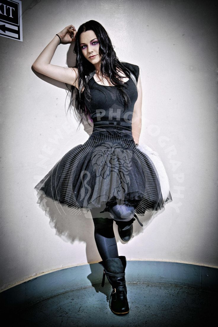 a woman in black dress and boots posing for the camera