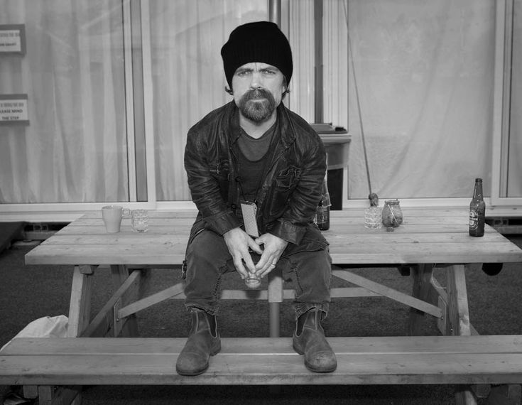 a black and white photo of a man sitting on a picnic table