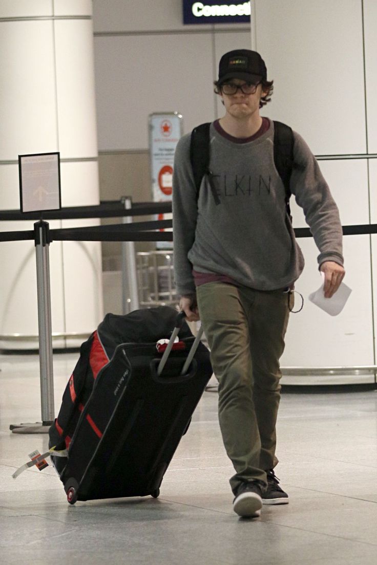 a man walking through an airport with his luggage