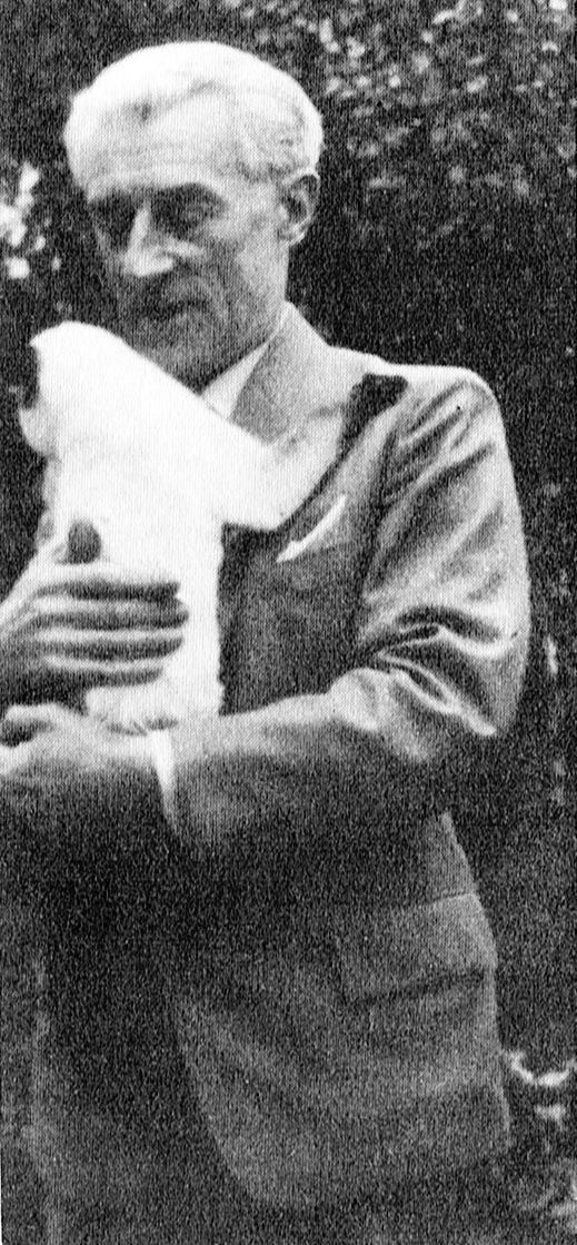 an old black and white photo of a man holding a cat