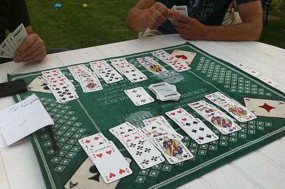 two men sitting at a table with playing cards