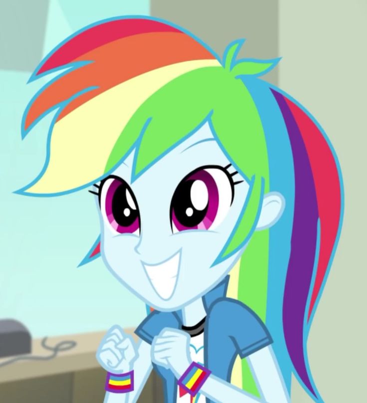 the rainbow pony is wearing a blue shirt and colorful hair, while standing in front of a computer desk