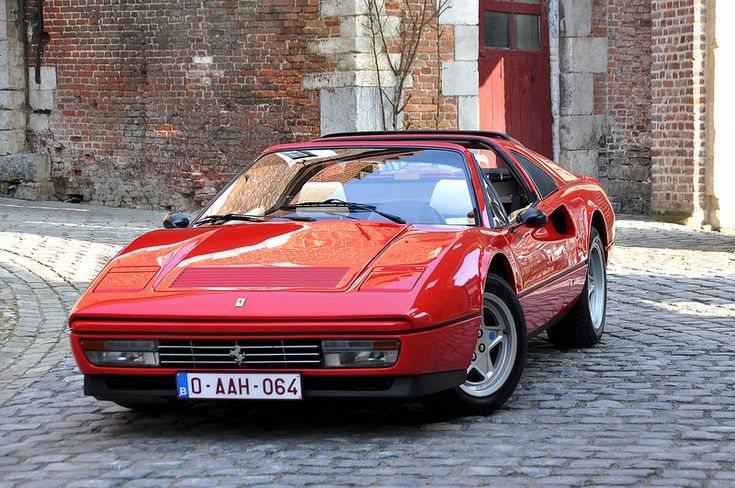 a red sports car parked in front of a brick building on a cobblestone street