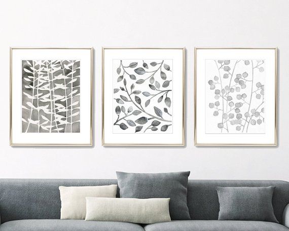 three black and white paintings on the wall above a couch