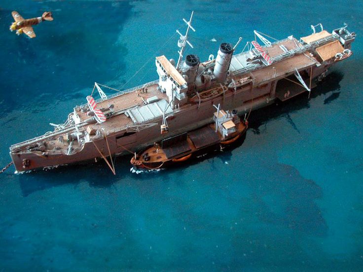 an aerial view of a ship in the water with two seagulls flying around