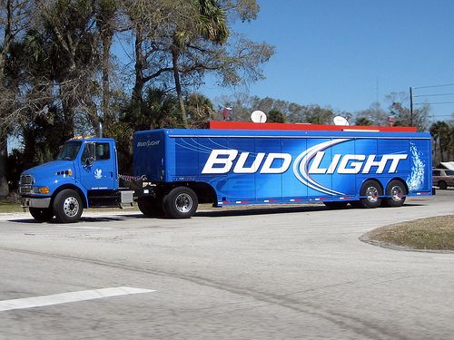 a bud light truck is parked on the side of the road in front of some trees