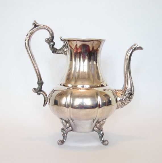 an antique silver teapot with handles and feet on a white background, the lid is slightly open