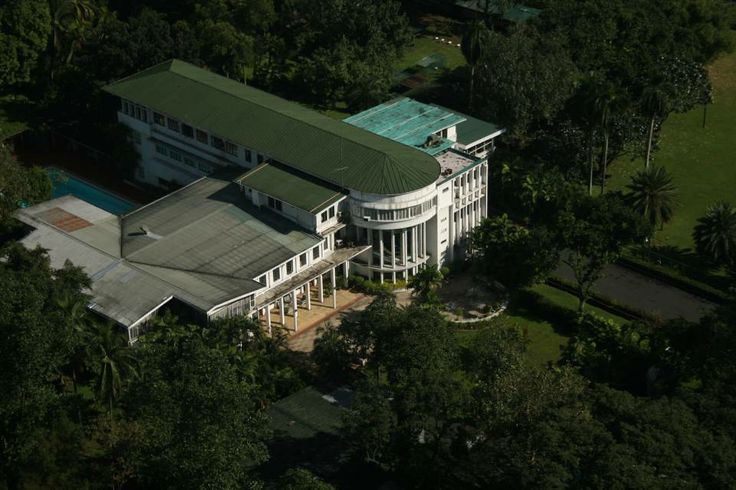 an aerial view of a large white house surrounded by trees