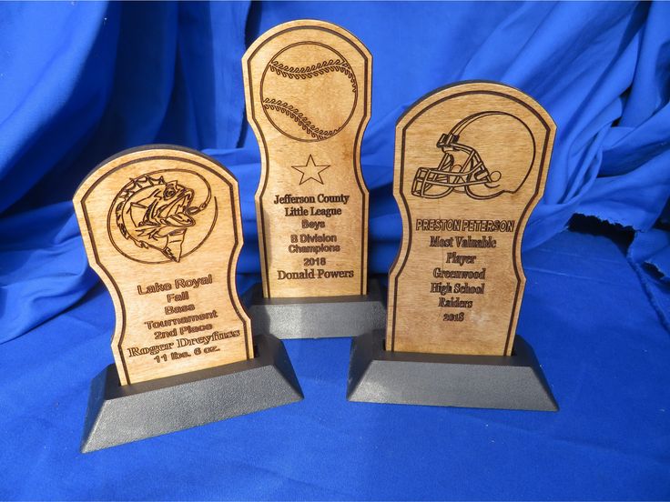 three wooden trophies with baseballs and helmets engraved on the sides, sitting on a blue background