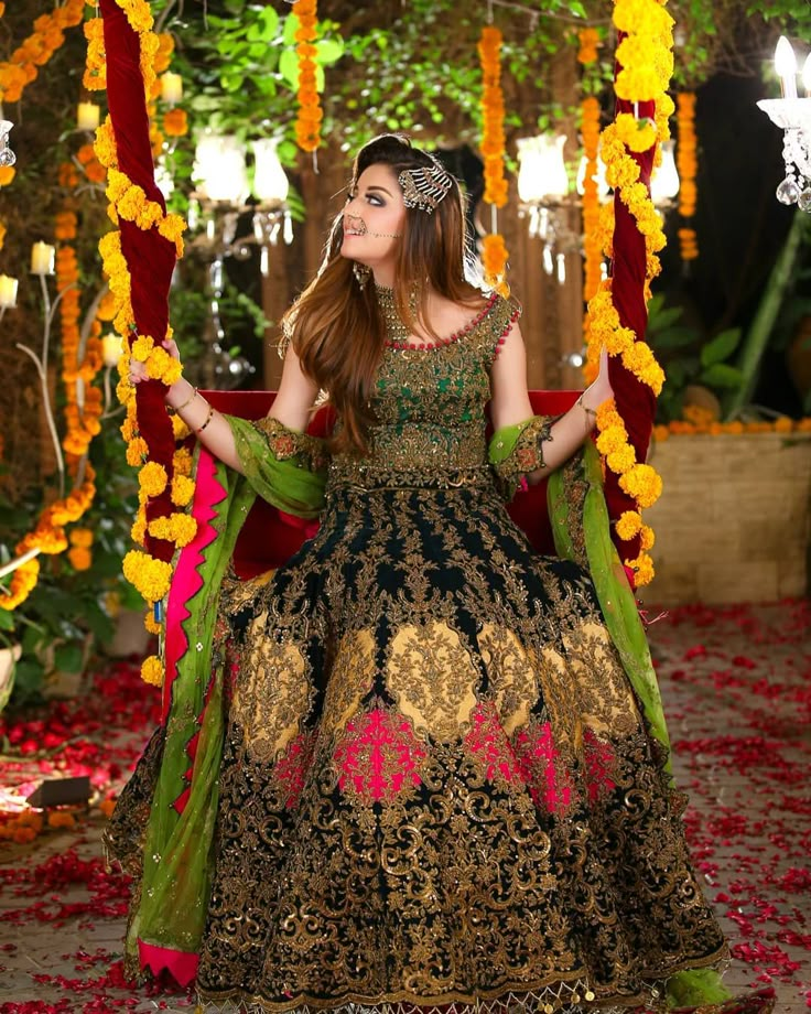 a woman in a black and gold dress standing under a canopy with flowers on it