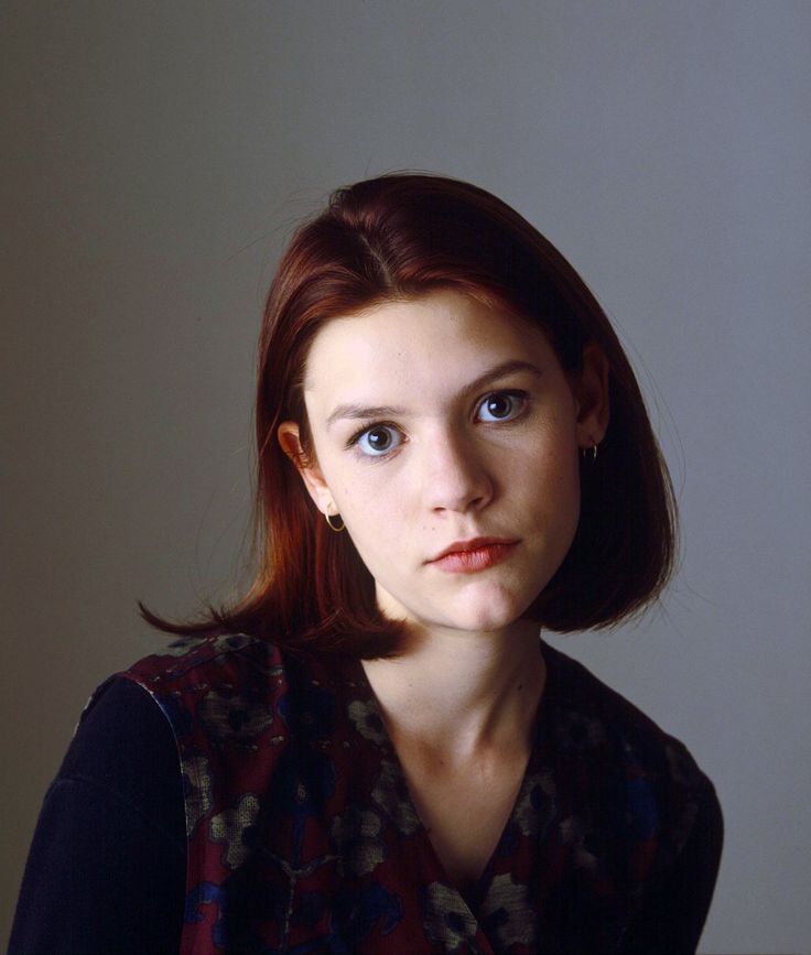 a woman with red hair and blue eyes is looking at the camera